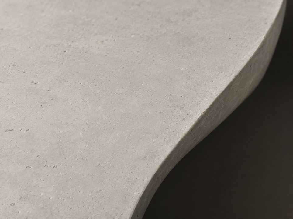 A close view along a smooth pale stone surface with one sweeping curved edge and a dark hollow.